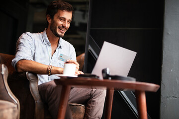 Businessman working on laptop and sitting in cafe. Young man holding credit card
