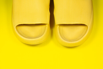 Yellow Summer Slippers on the yellow background. Pair of house indoors shoes. Minimalist, creative photo.