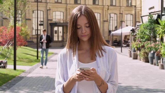 Relaxed young woman walking ath the city street, looking around. Enjoying nice day. Slowmotion.