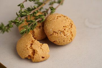 A macro close-up of green thyme branches and several bitter-sweet flavored macarons amaretti