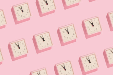 New Year countdown creative trendy pattern made with pink clocks on pastel pink background. 80s or 90s retro aesthetic fashion holiday concept. Minimal New Year party idea.