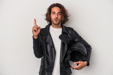 Young biker caucasian man holding a motorbike helmet isolated on gray background having some great...