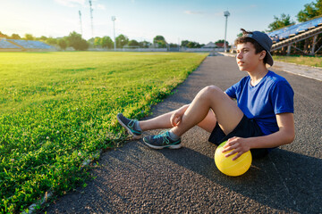 teen boy posing with ball at a stadium, a soccer field with green grass - sports and health concept