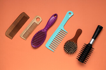 Wooden,plastic brushes,combs on the colorful orange background.Assortment of hair care tools