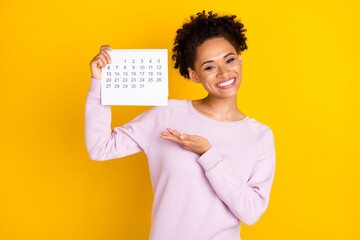 Photo of charming positive dark skin person hold demonstrate calendar isolated on yellow color background - obrazy, fototapety, plakaty