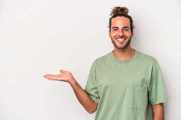 Young caucasian man isolated on gray background showing a copy space on a palm and holding another...