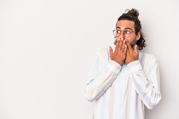 Young caucasian man isolated on gray background thoughtful looking to a copy space covering mouth with hand.