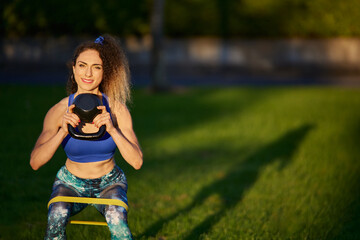 Fototapeta premium Caucasian woman personal trainer lifting heavy kettle with a treadmill on her knees