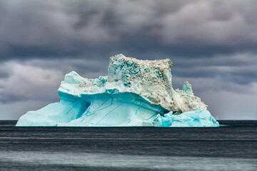 Iceberg floating in the sea off the coast of Disko Island, Greenland under dark overcast sky