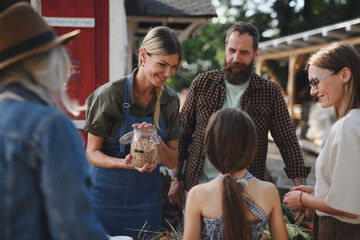 Obraz premium Little girl with her mother buying organic vegetables outdoors at community farmers market.