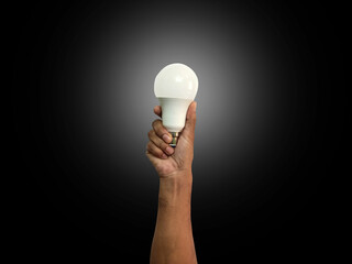 Hand holding an incandescent led light bulb. Power saving concept. Change your compact-fluorescent (CFL) bulbs with new LED light bulb.