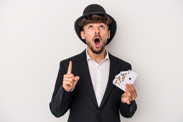 Young arab wizard man holding a magic cards isolated on white background pointing upside with...