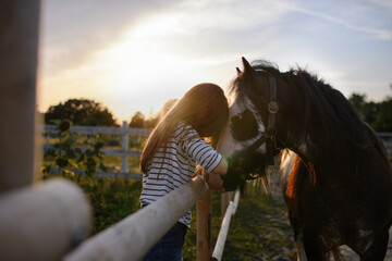 Little girl hugging horse outdoors at community farm.