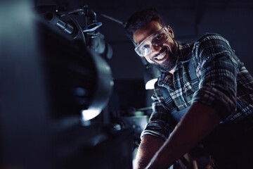 Fototapeta na wymiar Young african american industrial man during night shift indoors in metal workshop,looking at camera