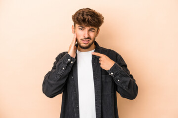 Young arab man isolated on beige background having a strong teeth pain, molar ache.