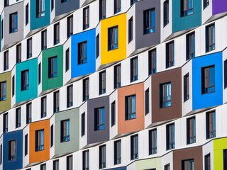 The multi-colored facade of a high-rise residential building. Rows of windows