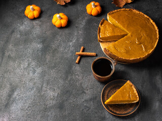 Homemade pumpkin pie, cup of coffee, crocheted small pumpkins, black table and copy space