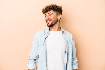 Young arab man isolated on beige background relaxed and happy laughing, neck stretched showing...