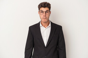 Young business caucasian man wearing headphones isolated on white background shrugs shoulders and open eyes confused.