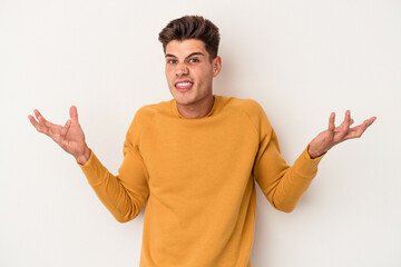 Young caucasian man isolated on white background doubting and shrugging shoulders in questioning...