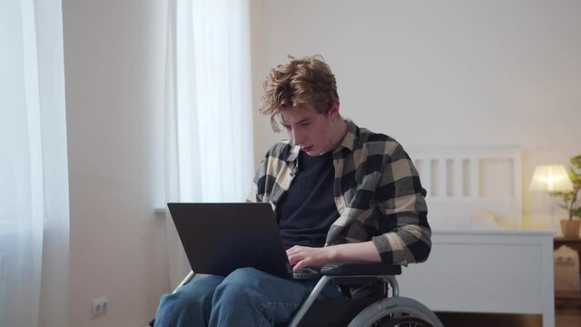 A disabled man is sitting in his wheelchair and looking through the Internet 