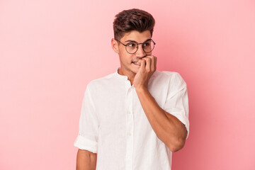 Young caucasian man isolated on pink background biting fingernails, nervous and very anxious.