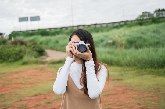 Young asian woman taking photo with retro film camera among the nature in the morning