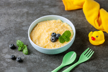 Corn porridge with berries in a bowl on the table. Baby food. Healthy breakfast