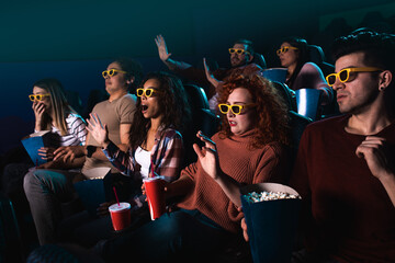 Group of people laughing while watching movie in cinema with 3D glasses.	