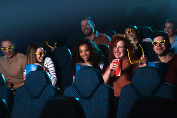 Group of cheerful people laughing while watching movie in cinema.