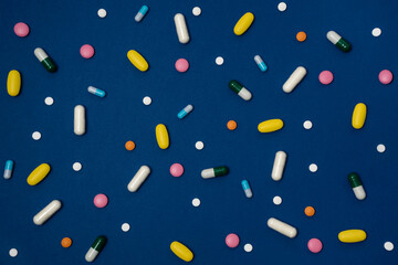 Excessive intake of drugs or vitamins. Blue background with a variety of vitamins or medications