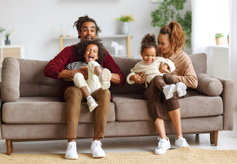 Joyful african american family parents and two little kids having fun together at home