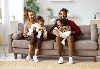 Joyful african american family parents and two little kids having fun together at home