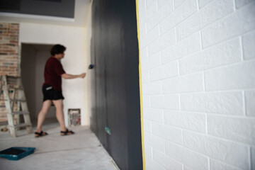 Roller Wall Painting. Worker paints wall, home renivation, focus is on the  white bricks. Painter at work. Home renovation