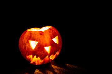 Jack's Lantern for Halloween on a black background. Scary apple face with a creepy smile