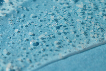 Smoothing scrub wash gel drop on blue background.