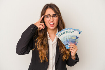 Young caucasian business woman holding banknotes isolated on white background showing a disappointment gesture with forefinger.