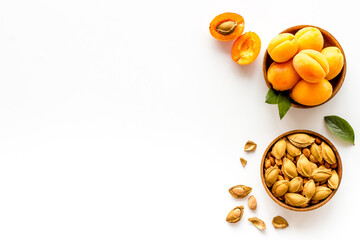 Wooden bowls of apricots and apricot kernel almond, top view