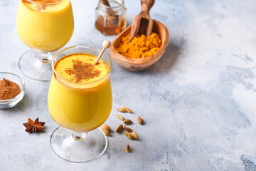 Turmeric golden milk latte with cinnamon sticks and honey. Healthy ayurvedic drink. Trendy Asian natural detox beverage with spices for vegans. Copy space.