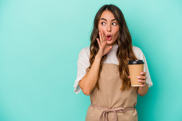 Young caucasian store clerk woman holding a takeaway coffee isolated on blue background is saying a secret hot braking news and looking aside