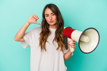 Young caucasian woman holding a megaphone isolated on blue background feels proud and self confident, example to follow.