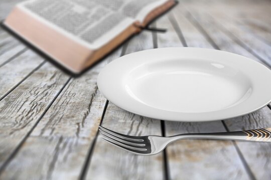 Fasting And Prayer. Christian Biblical Concept, Empty Plate With Holy Bible.