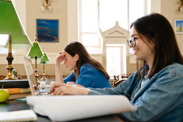 Young european student woman doing homework at library