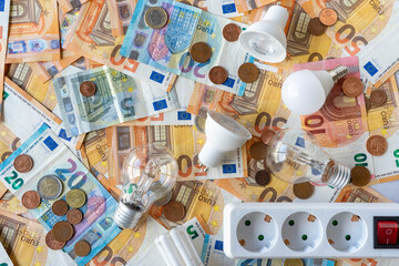 Electricity costs: Various types of light bulbs and electric socket on a background of euro banknotes and coins. . High quality photo