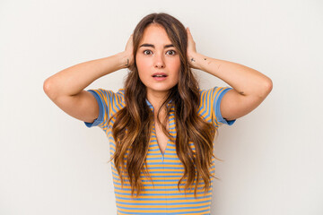 Fototapeta premium Young caucasian woman isolated on white background covering ears with hands trying not to hear too loud sound.