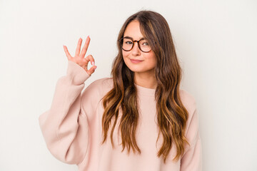 Young caucasian woman isolated on white background winks an eye and holds an okay gesture with hand.