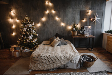 christmas bedroom interior in dark colors with a cozy large family bed decorated with a Christmas...