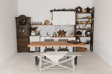 New Year's kitchen interior design in a light Scandinavian style with a table and decoration made of natural materials, garlands, oranges, holiday