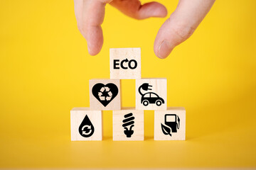 Ecology concept with icons on wooden cubes, yellow background.