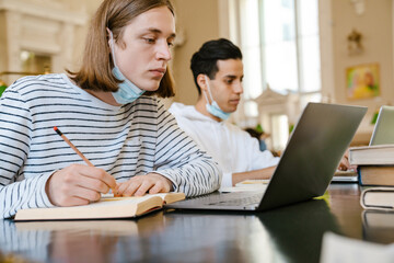 Young multiracial student man doing homework at library